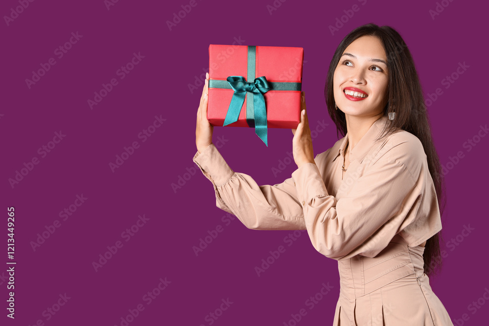 Beautiful young Asian woman with gift box on purple background Beautiful young Asian woman with gift box on purple background