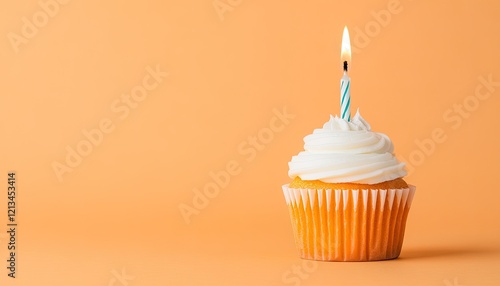 A beautifully decorated cupcake with a lit candle set against a soft orange background photo