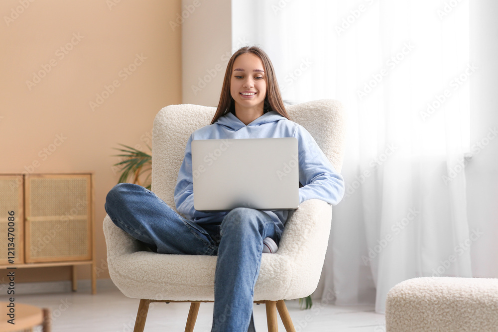 Young woman sitting on armchair and using laptop in living room Young woman sitting on armchair and using laptop in living room