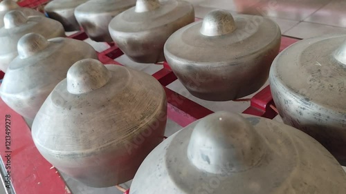 Gamelan Bonang instruments arranged in rows with red metal frame holding them photo