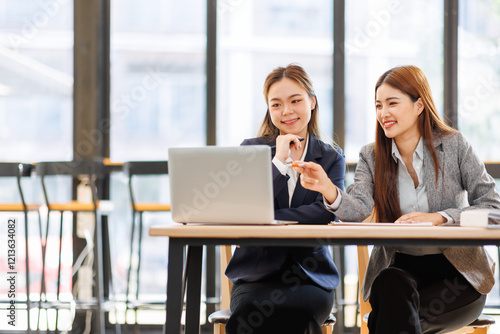 Wallpaper Mural Two asian women analyzing documents while sitting on a laptop screen in office. Woman executives at work in office discussing some paperwork. Torontodigital.ca