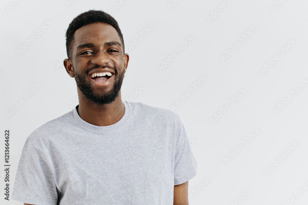 Confident smiling man in casual grey tshirt posing against white background for lifestyle and fashion concepts Confident smiling man in casual grey tshirt posing against white background for lifestyle and fashion concepts