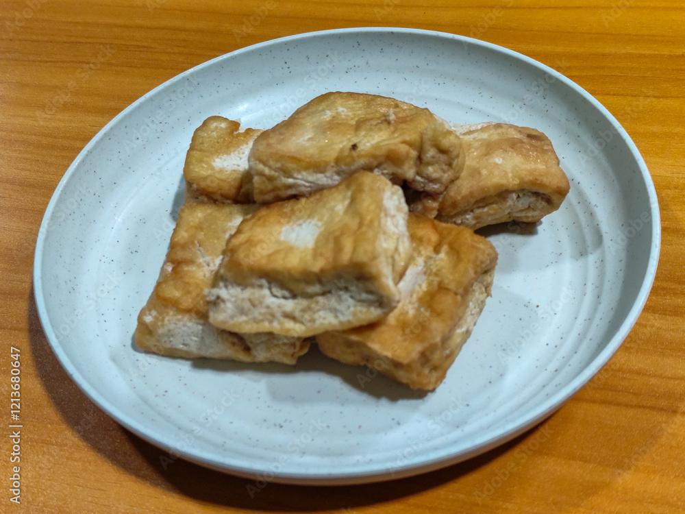 Fried tofu on a white plate. Traditional Indonesian snack. Fried tofu on a white plate. Traditional Indonesian snack.
