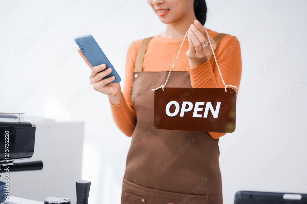 Asian barista with a beautiful face, wearing overalls, smiling warmly while holding a shop opening sign, welcoming customers to the counter bar at the front of a vibrant coffee shop Asian barista with a beautiful face, wearing overalls, smiling warmly while holding a shop opening sign, welcoming customers to the counter bar at the front of a vibrant coffee shop