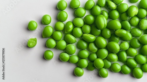 Bunch of green peas are spread out on a white surface. The peas are all different sizes and some are slightly broken. Concept of abundance and variety, as well as the idea of fresh, healthy food photo