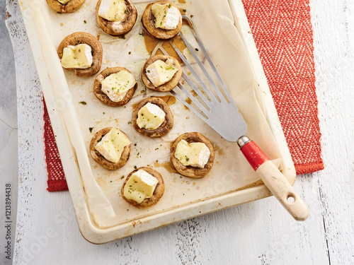 A tray holds freshly baked mushroom appetizers topped with melted cheese, showcasing delicious bite-sized treats perfect for entertaining guests photo