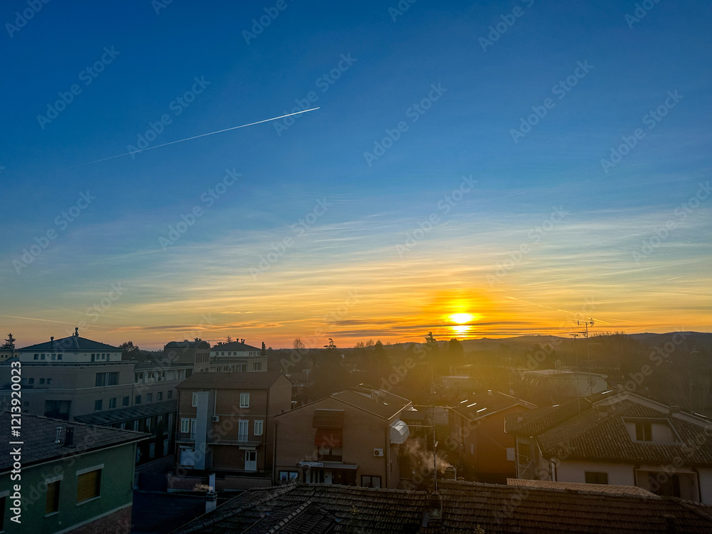 Fototapeta premium As the sun slowly sets down over the sprawling city, the silhouettes of buildings rise prominently in the foreground against the vibrant sky