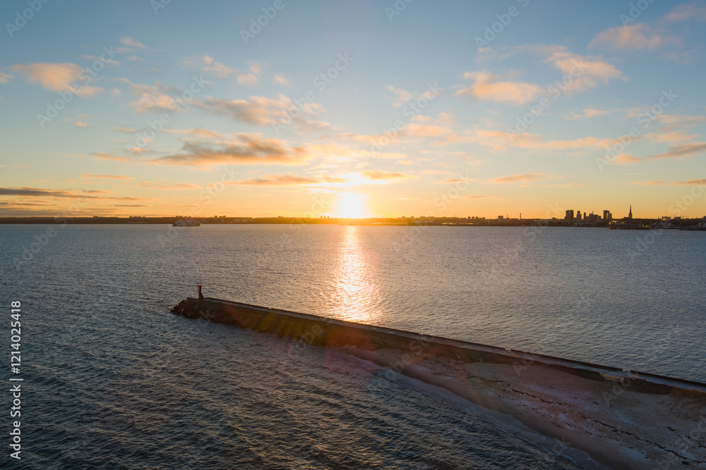 Obraz premium Sunrise over Paljassaare and Tallinn bay: Drone view of the lighthouse and breakwater in a low-snow winter morning.