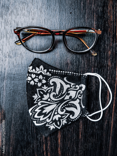 Obraz na płótnie Stylish glasses and a handmade floral mask placed on a dark wooden table, creating an appealing contrast. w salonie