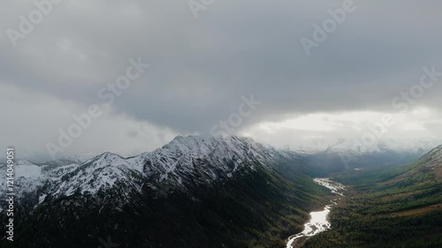 Snow-dusted rocky cliffs rising against a backdrop of misty, snow-covered mountains. 
 photo