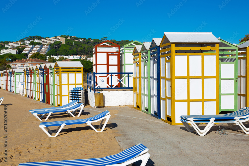 Colorful beach huts and sunbeds inviting tourists to relax on sandy shore