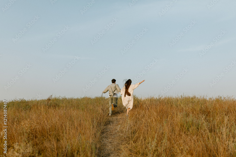 Young couple running through the hills. Love concept. Free spirit in nature. Beautiful field on the hills. Freedom concept. Uniting with nature. Active lifestyle Young couple running through the hills. Love concept. Free spirit in nature. Beautiful field on the hills. Freedom concept. Uniting with nature. Active lifestyle