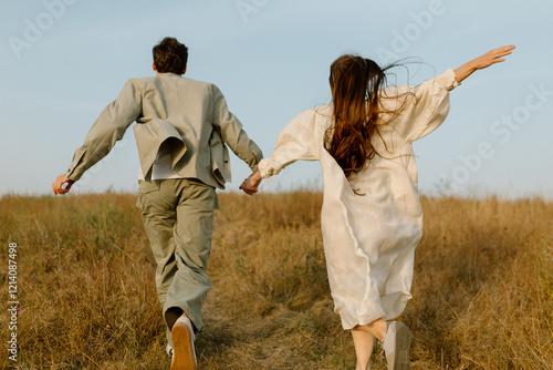 Young couple running through the hills. Love concept. Free spirit in nature. Beautiful field on the hills. Freedom concept. Uniting with nature.  Active lifestyle