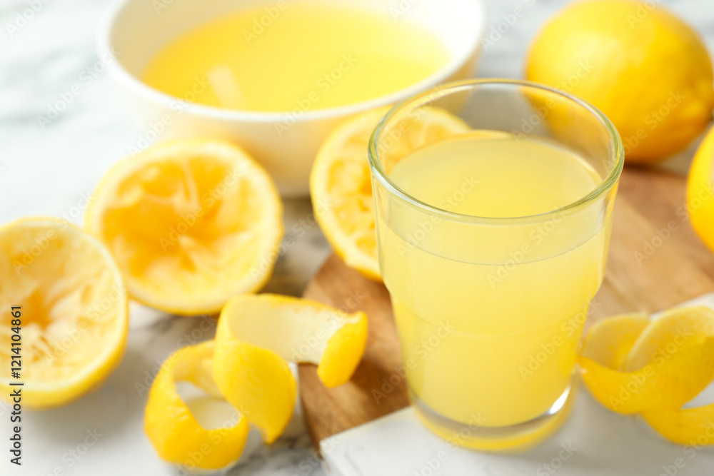 Fototapeta premium Glass of fresh lemon juice and squeezed fruits on table, closeup