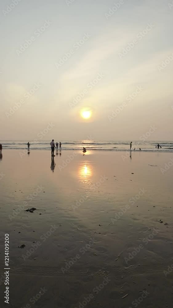 Sunset On Sandy Beach With Rolling Waves And People Enjoying At Evening Sunset On Sandy Beach With Rolling Waves And People Enjoying At Evening