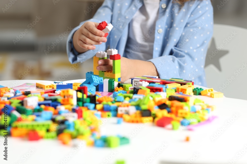 Girl playing with building blocks at white table indoors, closeup Girl playing with building blocks at white table indoors, closeup