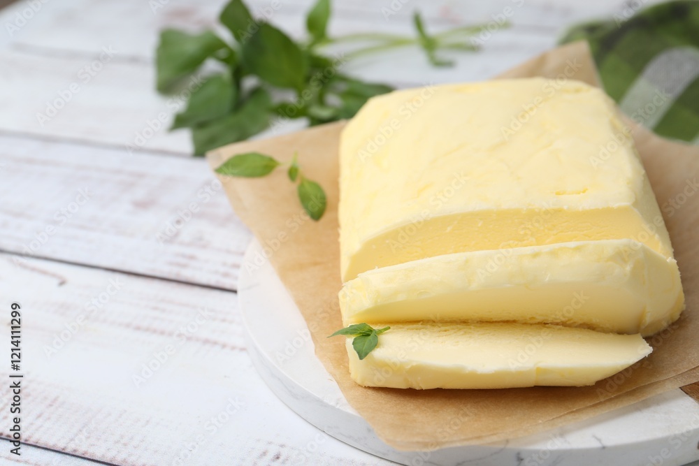 Cut brick of butter and basil on white wooden table, closeup. Space for text Cut brick of butter and basil on white wooden table, closeup. Space for text