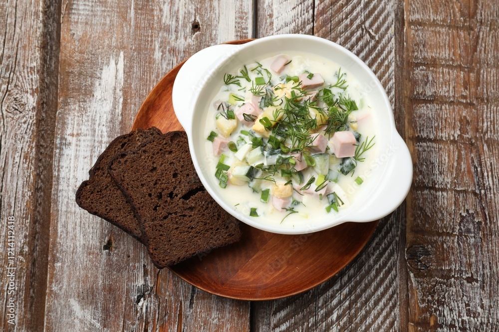 Delicious okroshka soup in bowl and bread on wooden table, top view Delicious okroshka soup in bowl and bread on wooden table, top view