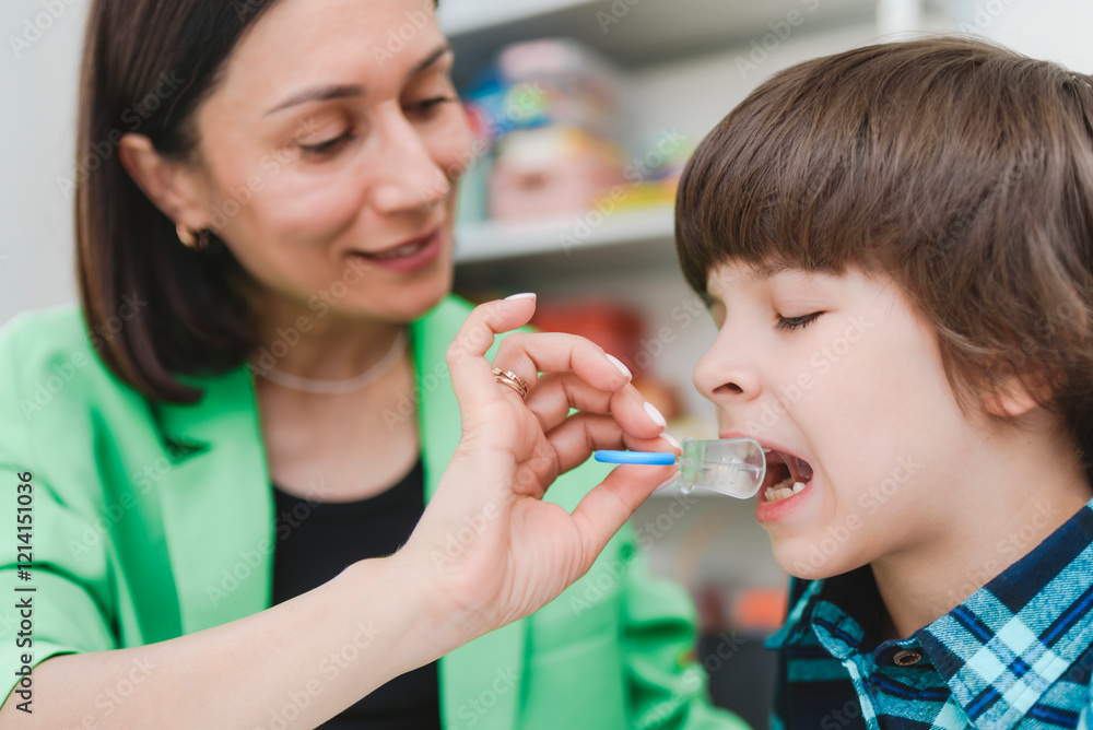 A female speech therapist shows a boy an orthodontic plate to correct his bite.