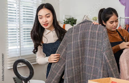 Couple selling clothes online, inspecting stylish plaid jacket and preparing other items in their cozy workspace photo