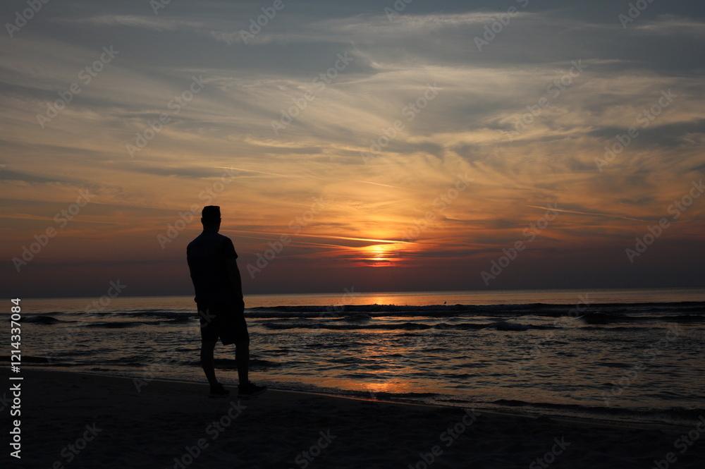 Summer closeup sunset sea sky landscape. Beautiful beach reflections calm waves, soft sandy beach. Soft silhouette of a person on the seashore at sunset Summer closeup sunset sea sky landscape. Beautiful beach reflections calm waves, soft sandy beach. Soft silhouette of a person on the seashore at sunset