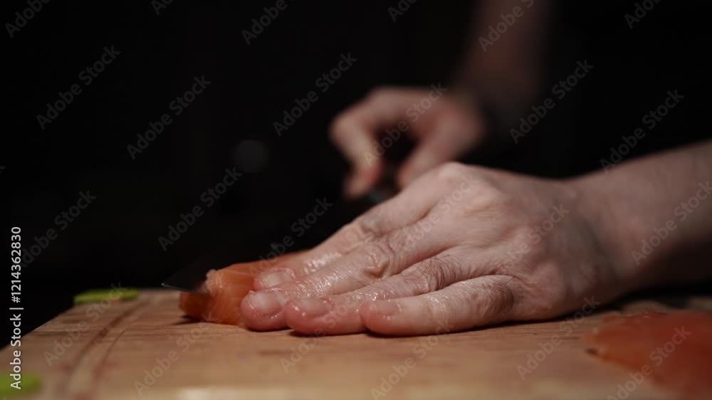 Close-Up of Hands Slicing Fresh Salmon Fillet on a Dark Background Close-Up of Hands Slicing Fresh Salmon Fillet on a Dark Background