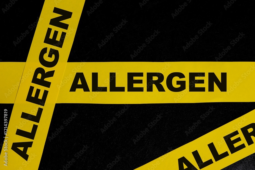 Food allergen content caution and warning concept. Yellow barricade tape with word in dark black background.