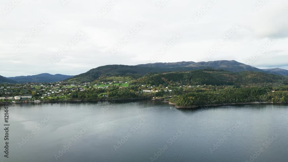 The video presents a serene view of a peninsula from above. A coastal settlement, dense vegetation, water, and mountains are visible, creating an impression of peace and natural beauty. The video presents a serene view of a peninsula from above. A coastal settlement, dense vegetation, water, and mountains are visible, creating an impression of peace and natural beauty.