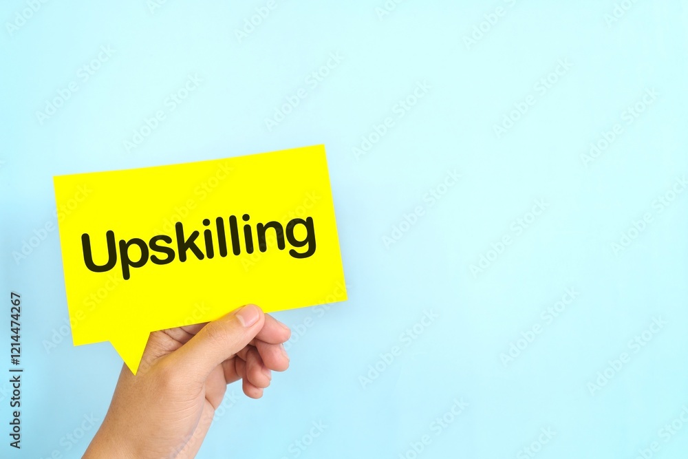 Human hand holding yellow speech bubble with written phrase Upskilling. Upskilling in workplace.