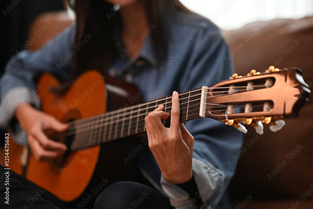 Fototapeta premium A close up of a guitarist hands pressing the strings on the fretboard of an acoustic guitar, highlighting focus and technical skill