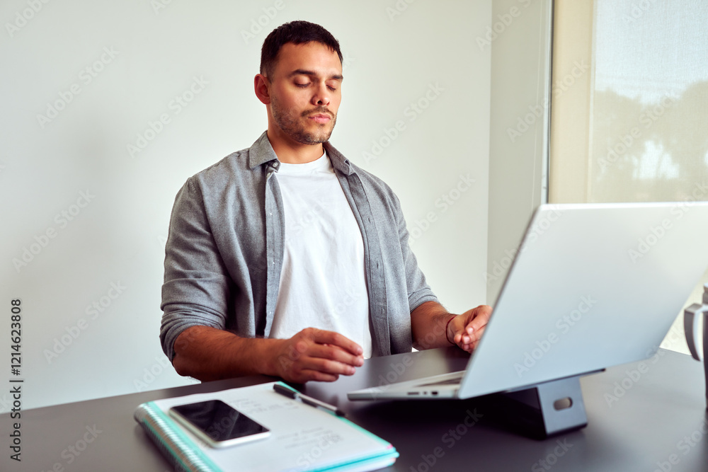 Young business man meditating at workplace with eyes closed, practicing mindfulness meditation during work on laptop Young business man meditating at workplace with eyes closed, practicing mindfulness meditation during work on laptop