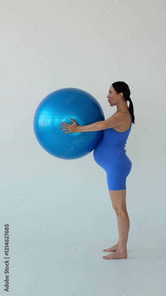 Positive middle aged Caucasian woman performing pregnancy fitness exercise using fitball on white background. Healthy and sporty lifestyle. Vertical video. Positive middle aged Caucasian woman performing pregnancy fitness exercise using fitball on white background. Healthy and sporty lifestyle. Vertical video.