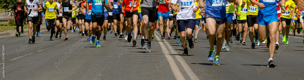 large group runners races down wide city street during marathon large group runners races down wide city street during marathon