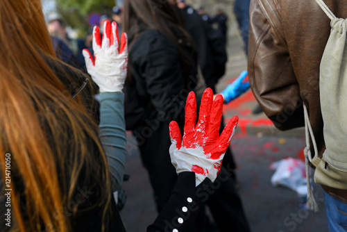 Obraz na plátne Red painted hands with gloves raised in protest.