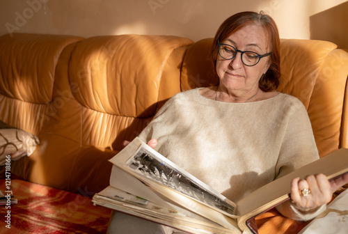 Foto Senior lady looking at old photographs in the album, remembering her past and her baby, family
