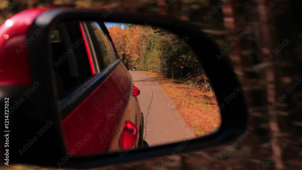 The sun is reflected in the mirror, evening road. View in the side rear view mirror of a red car driving along the highway The sun is reflected in the mirror, evening road. View in the side rear view mirror of a red car driving along the highway