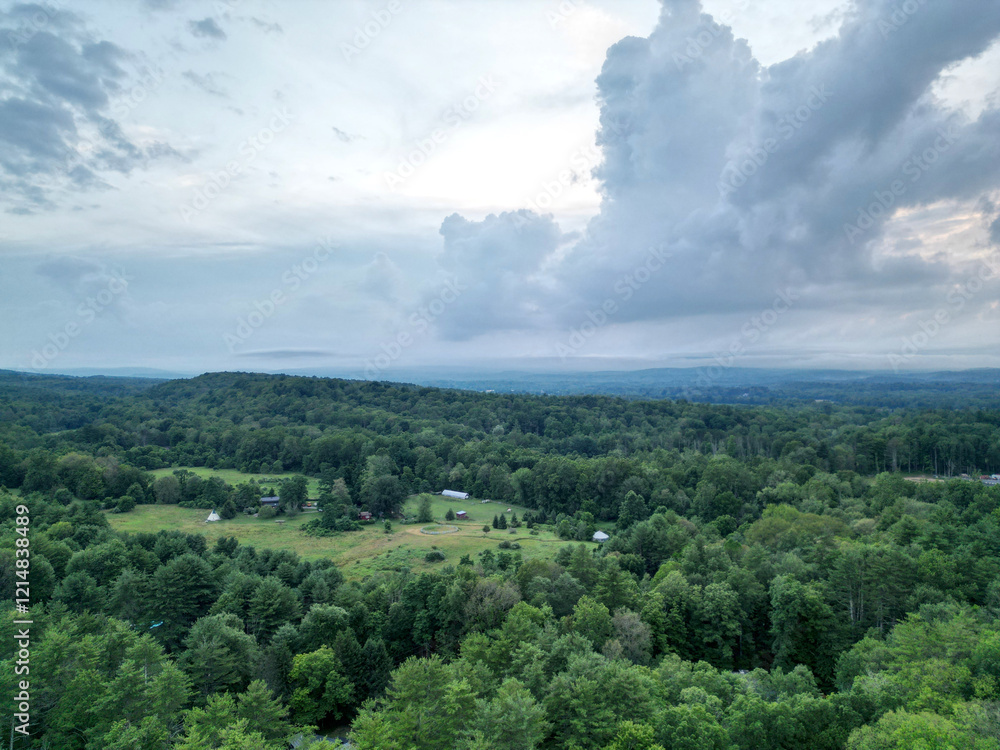 Fototapeta premium view of catskill mountains at sunset (wide angle aerial mountain vista in catskills hudson valley slide mountain wilderness hiking area) dramatic huge puffy clouds sky cloud formation farm rural area