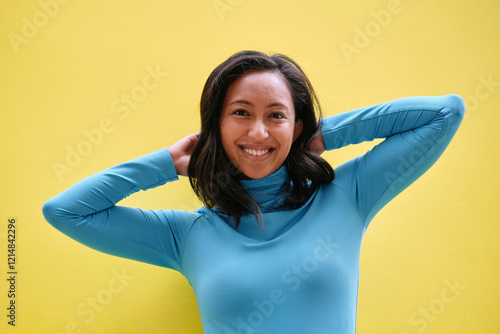 Young woman holding hair smiling on yellow background photo