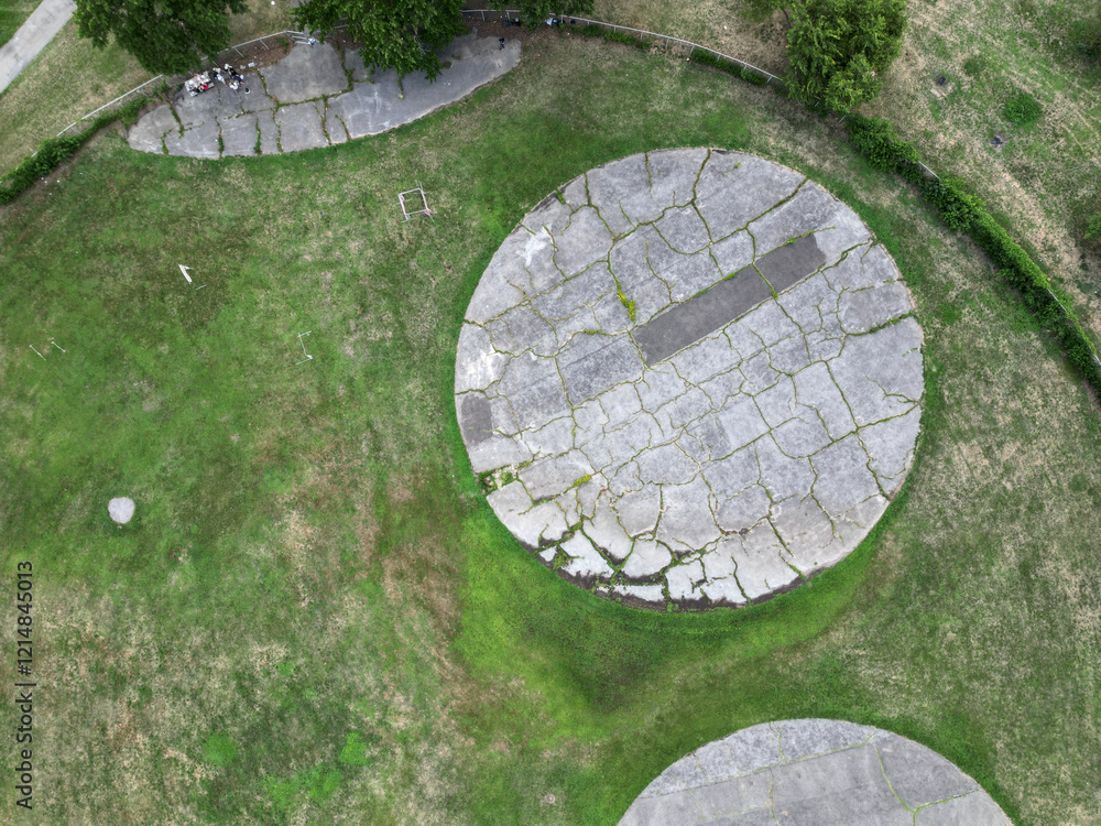 overgrown concrete circles round paths at old model aircraft field in new york city (flushing meadows corona forest park) landing takeoff area drone flight looking down cement grass strip green overgrown concrete circles round paths at old model aircraft field in new york city (flushing meadows corona forest park) landing takeoff area drone flight looking down cement grass strip green