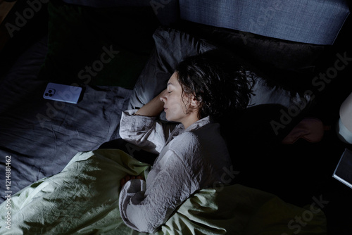 High angle shot of adult woman restoring her energy while sleeping in comfortable bed in room illumed by silver moonlight photo