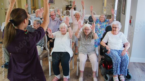 Carer Leading Group Of Seniors In Fitness Class In Retirement Home