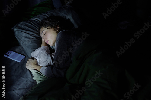 High angle shot of woman having nightmare while sleeping in bed in dark room illumed with moonlight photo