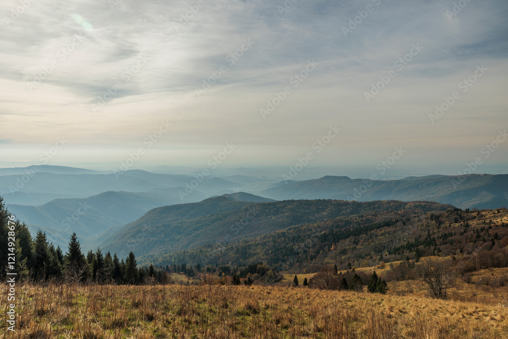 Obraz premium vista panoramica in alta quota su un ambiente naturale tra le montagne e le colline lungo il confine tra Italia e Slovenia, di mattina, a fine autunno, con cielo leggermente nuvoloso