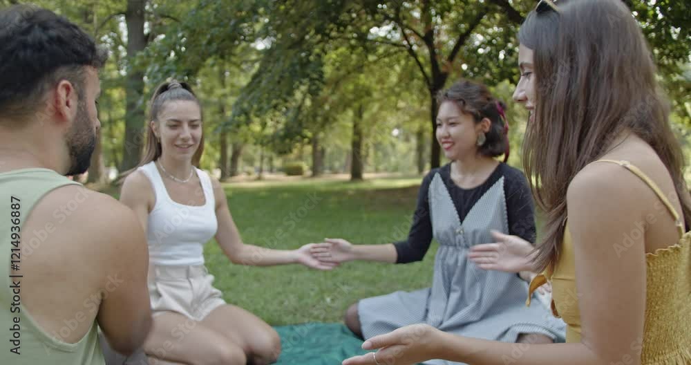 Friends gather in a park during summer, enjoying a picnic and playing a card game. Laughter and happiness fill the air as they create memories together. Friends gather in a park during summer, enjoying a picnic and playing a card game. Laughter and happiness fill the air as they create memories together.
