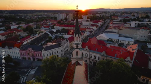 Majestic beautiful historic church with a rooster on the roof in the city at sunset, drone footage, Lučenec, Slovakia photo