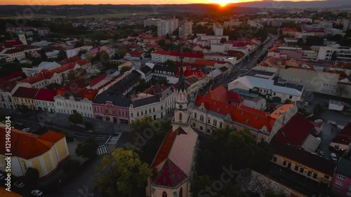 Majestic beautiful historic church with a rooster on the roof in the city at sunset, drone footage, Lučenec, Slovakia photo