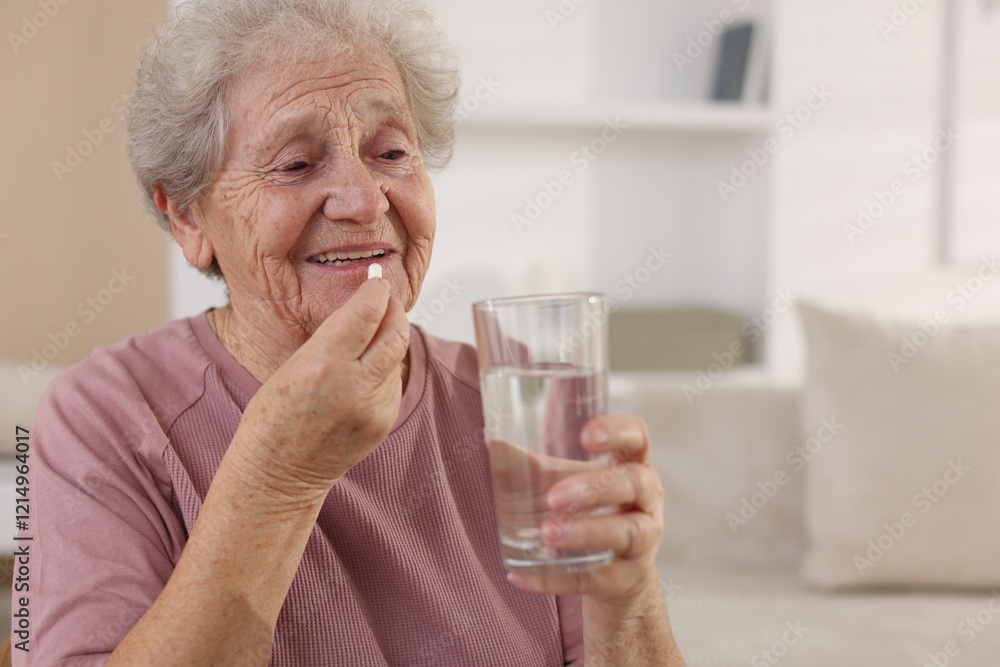 Smiling senior woman with glass of water taking pill at home. Space for text Smiling senior woman with glass of water taking pill at home. Space for text
