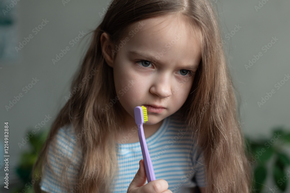 Caucasian female child contemplating toothbrush in striped shirt Caucasian female child contemplating toothbrush in striped shirt