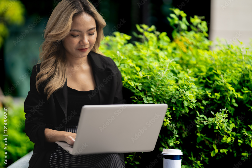 Young professional using her laptop while seated in a green urban space. A portrayal of a modern career lifestyle, highlighting technology, focus, and outdoor productivity. Young professional using her laptop while seated in a green urban space. A portrayal of a modern career lifestyle, highlighting technology, focus, and outdoor productivity.