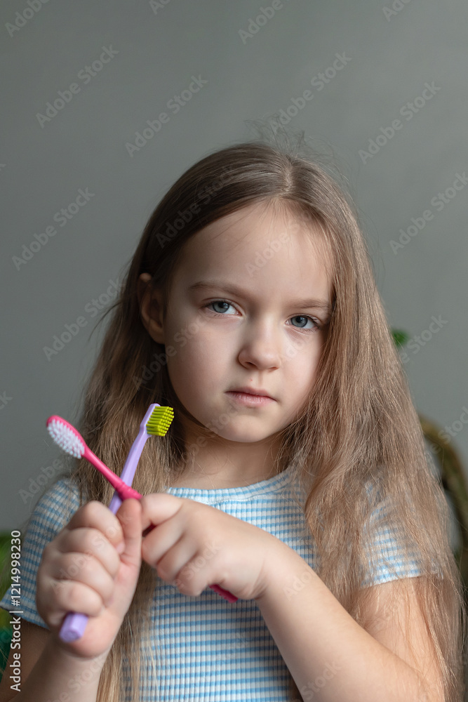 Caucasian female child holding toothbrushes with determined expression